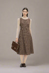 Woman wearing a brown plaid dress holding a brown bag